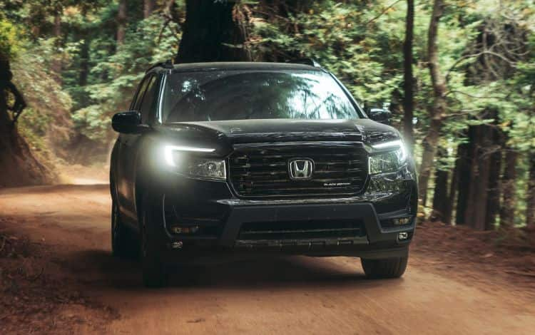 2025 Honda Passport Black Edition Front shot in Crystal Black in Crystal Black Pearl driving on forest road