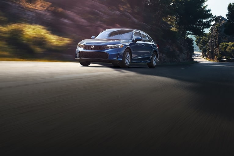 2027 Honda Civic LX in Blue Lagoon Pearl driving on a winding road (Compact Sedan)